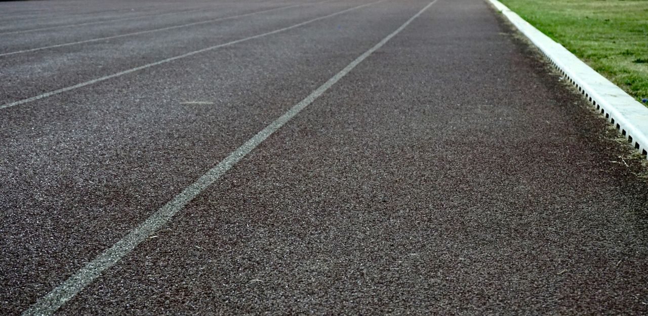 pexels photo 368690 368690 Detailed view of an empty athletic running track lane with visible surface texture and grass edge.